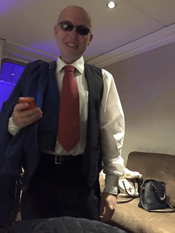 Luke in a suit, waistcoat and red tie, dressed for a shift as a croupier
