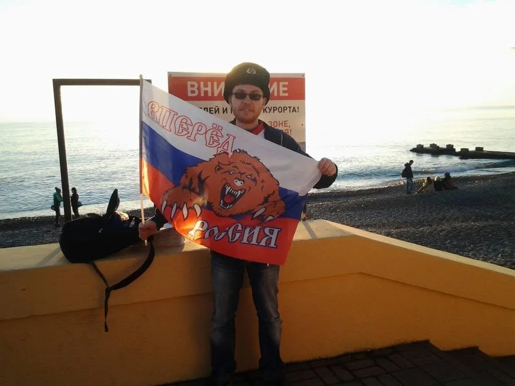 Luke holding a Russian flag on the seafront at Sochi