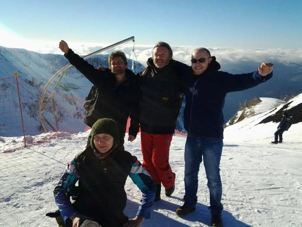 Luke with two friends on a snowy mountain slope, arms raised in celebration